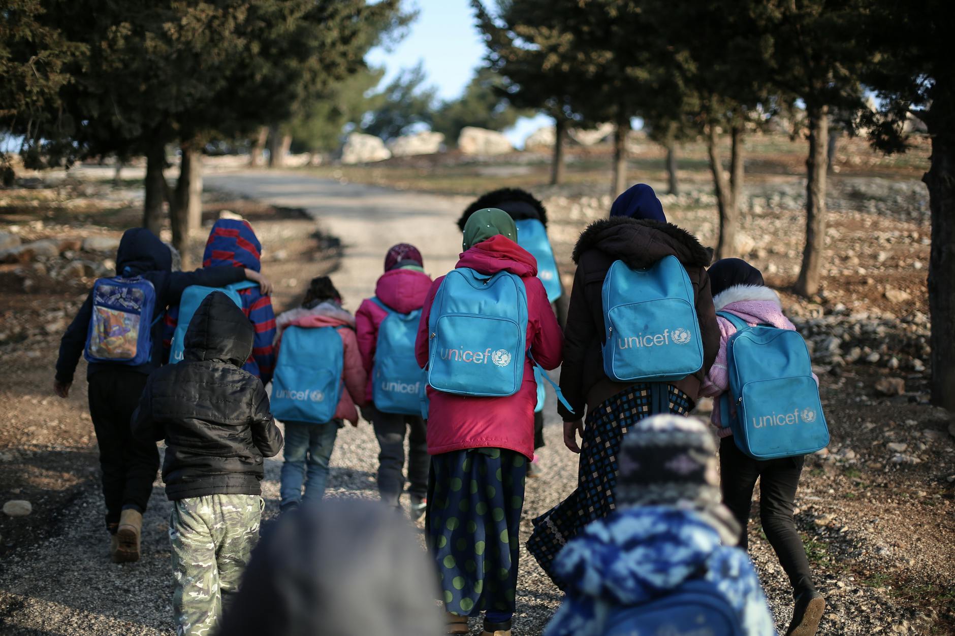 children walking with unicef backpacks