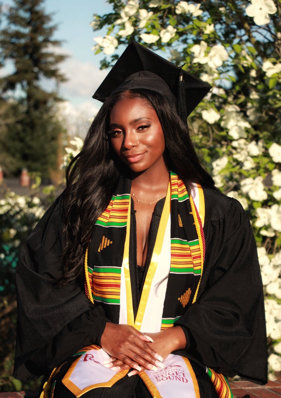 young graduate in cap and gown standing outdoors