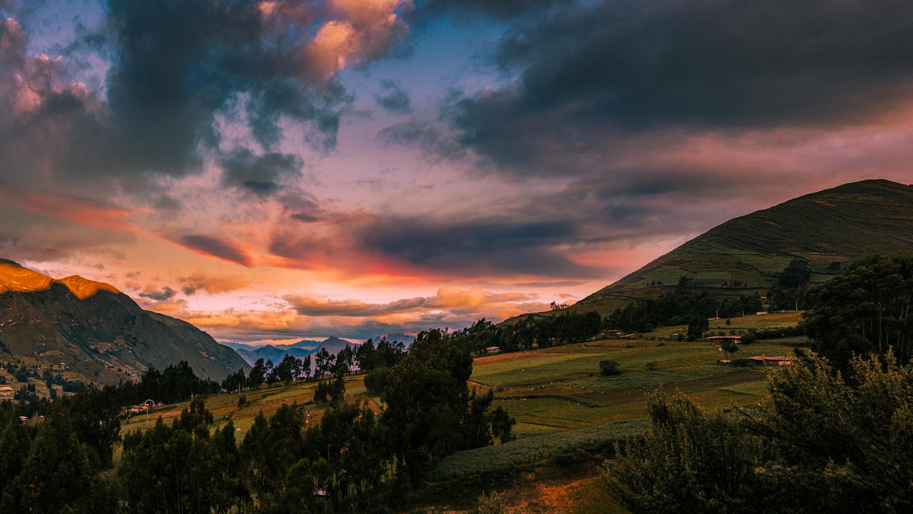 a sunset over a valley with mountains and clouds