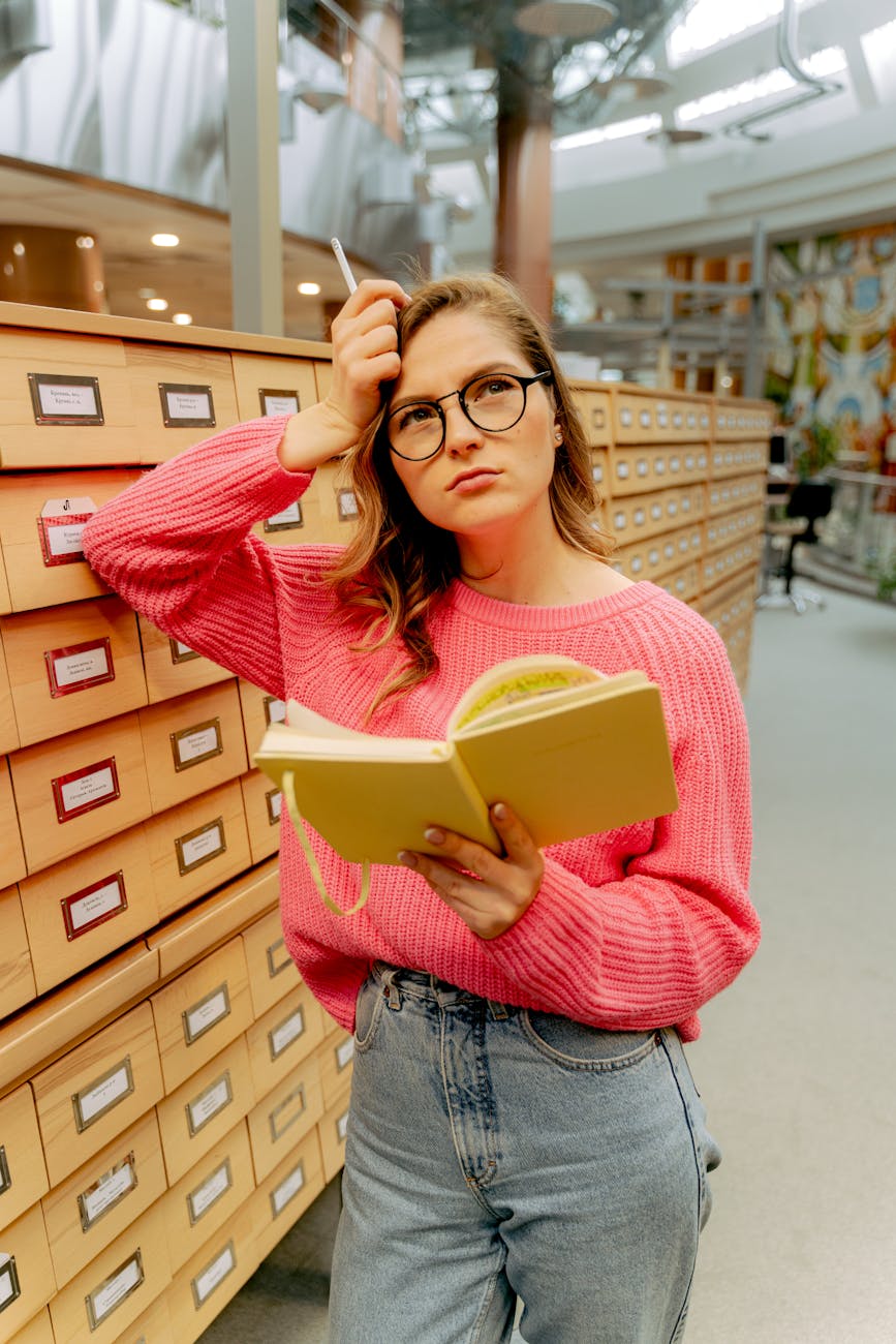 woman wearing eyeglasses and holding book in library