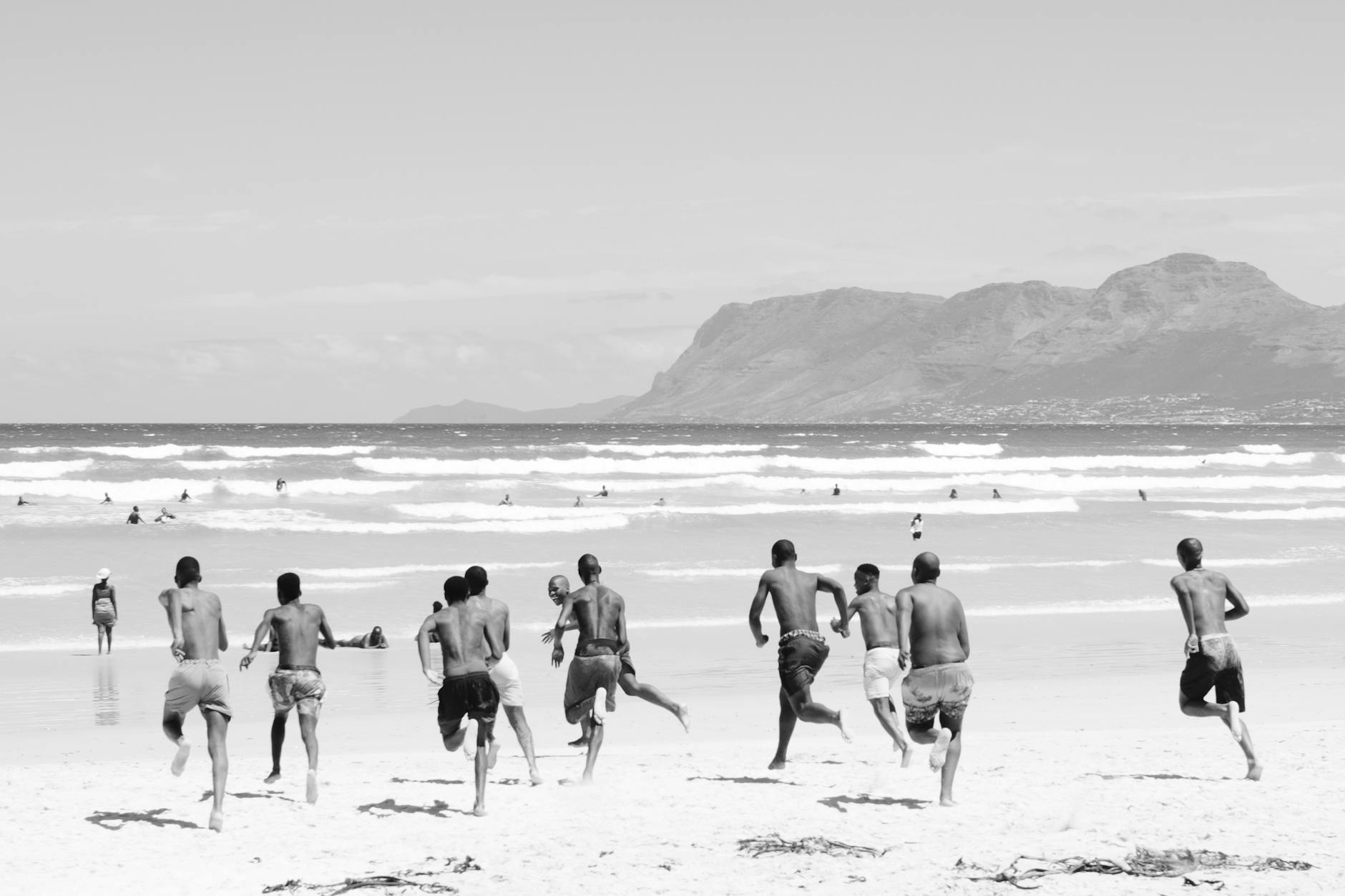 boys running on a beach towards ocean waves