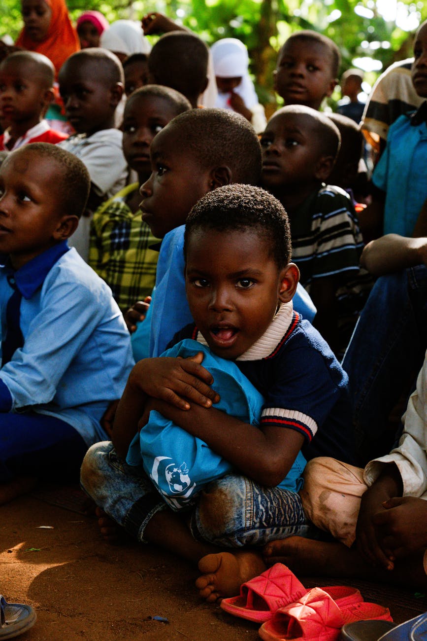 group of children sitting outdoors in shade