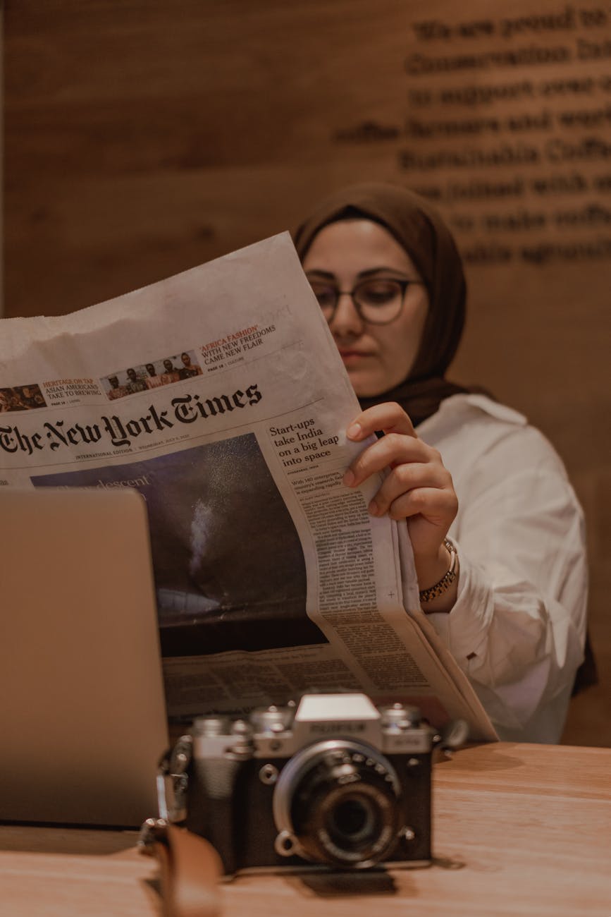 woman sitting at the table and reading a newspaper