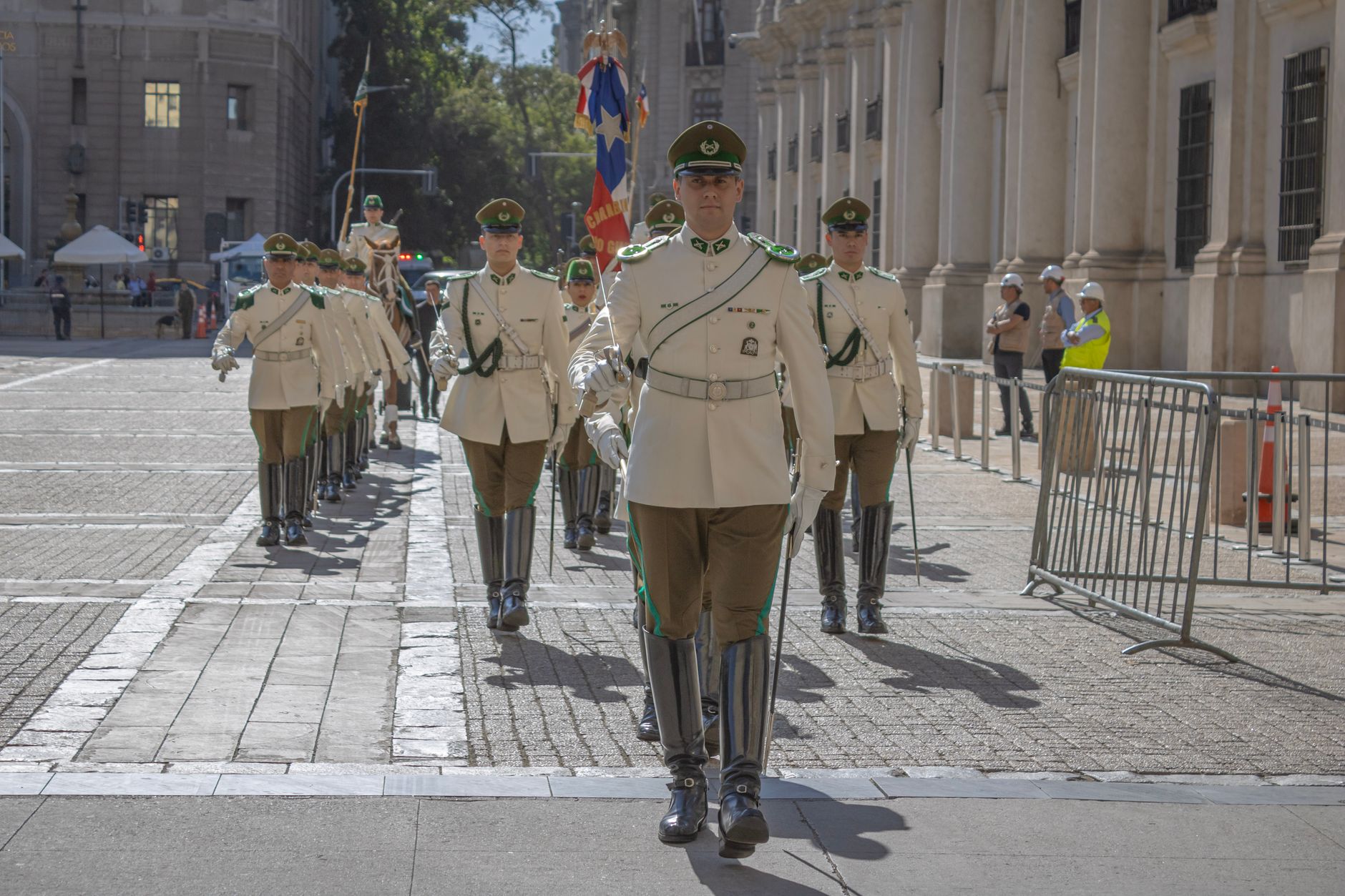 A military parade with uniformed guards marching in Santiago, Chile on a sunny day.