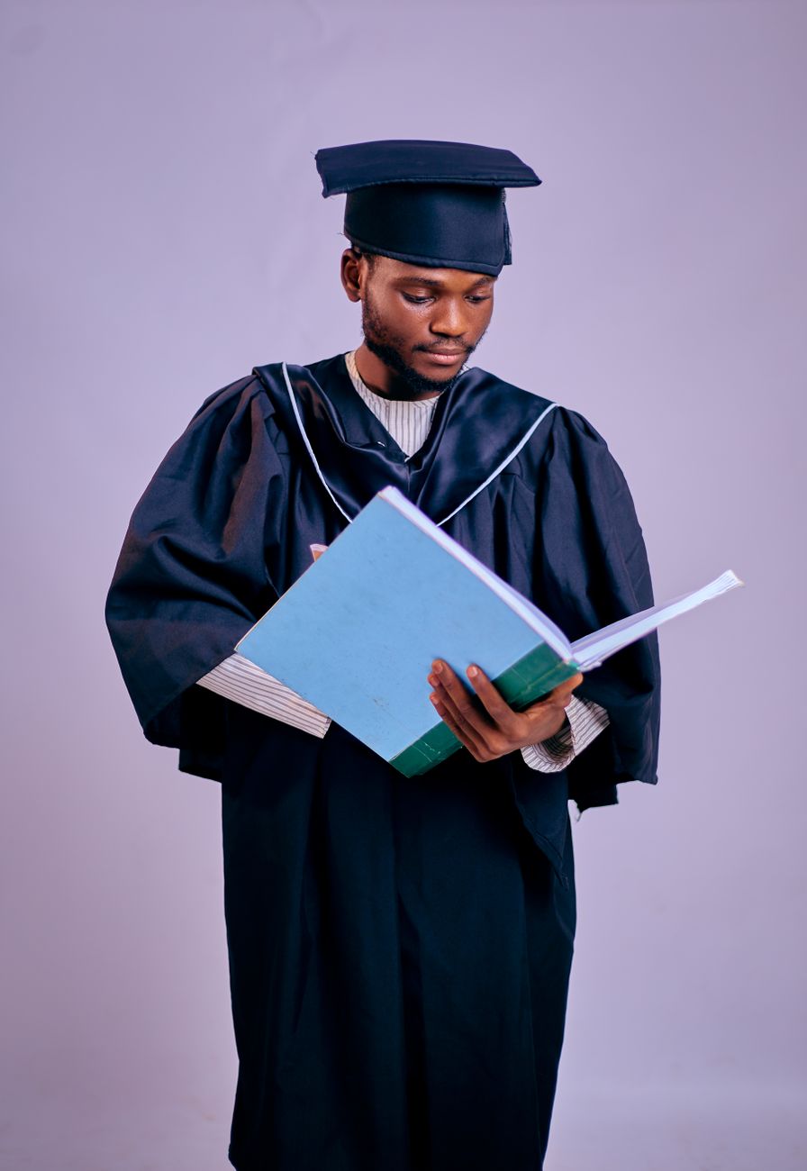 young graduate holding book in cap and gown
