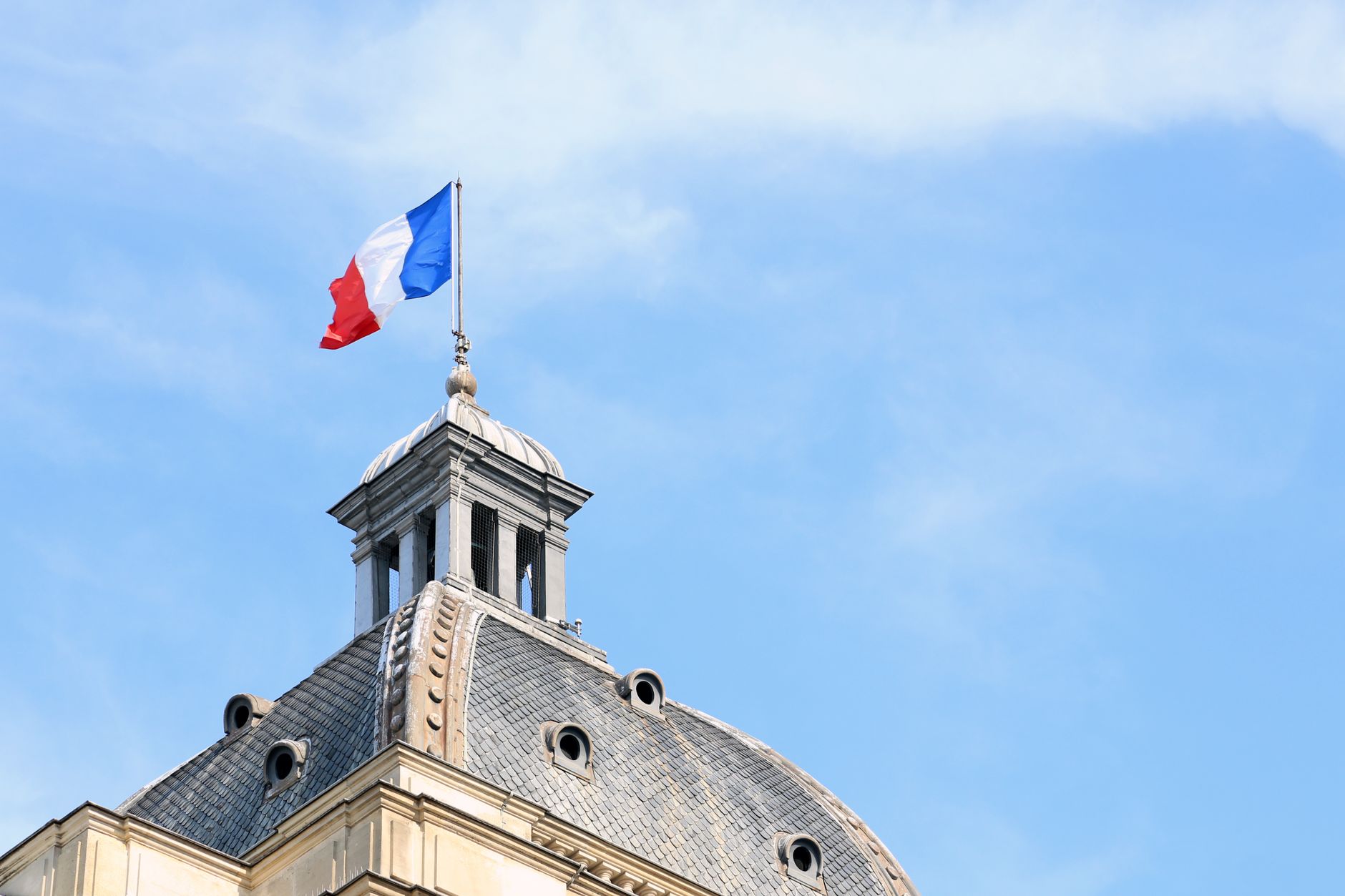 french flag atop historic parisian building