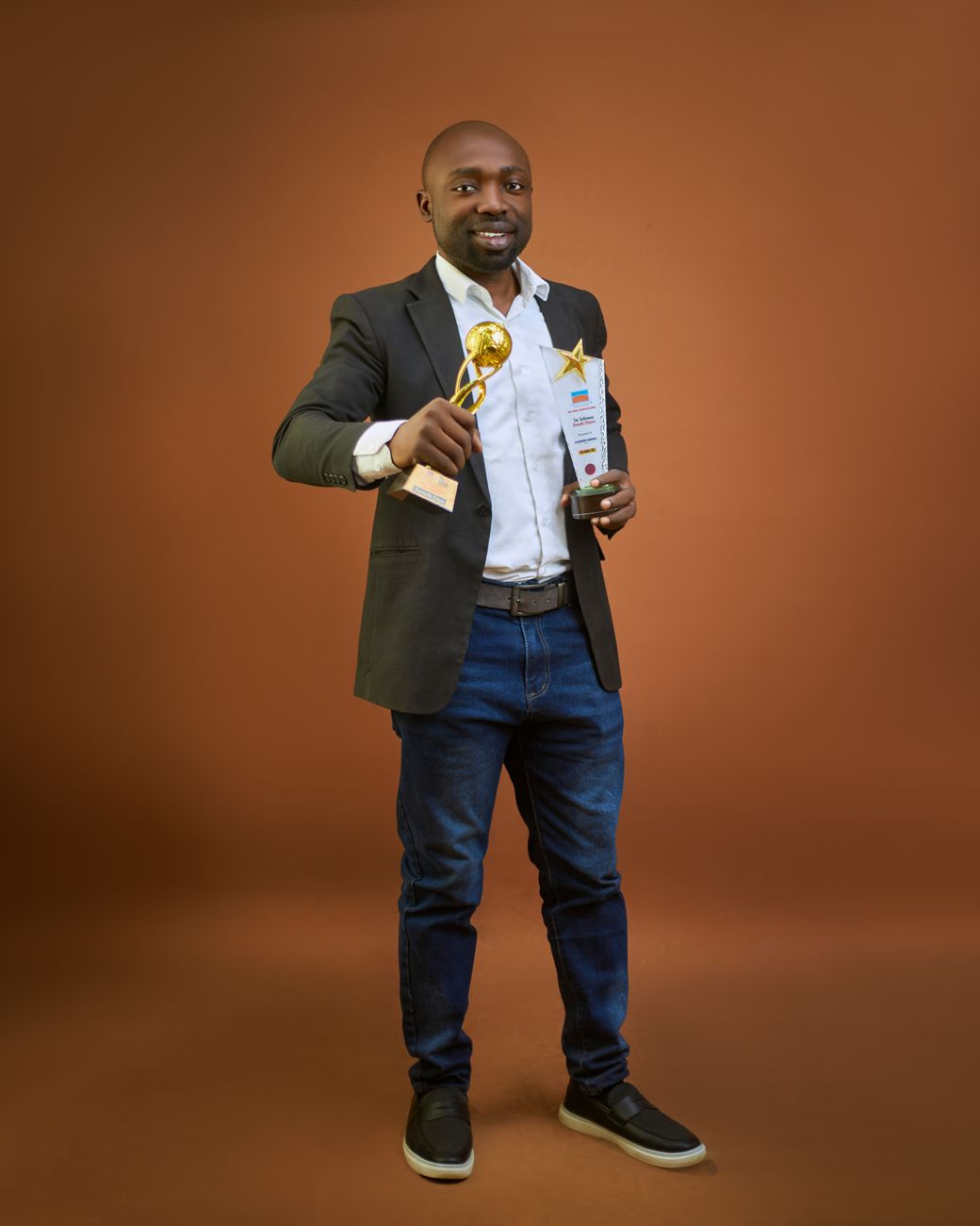 proud man holding two trophies on brown background