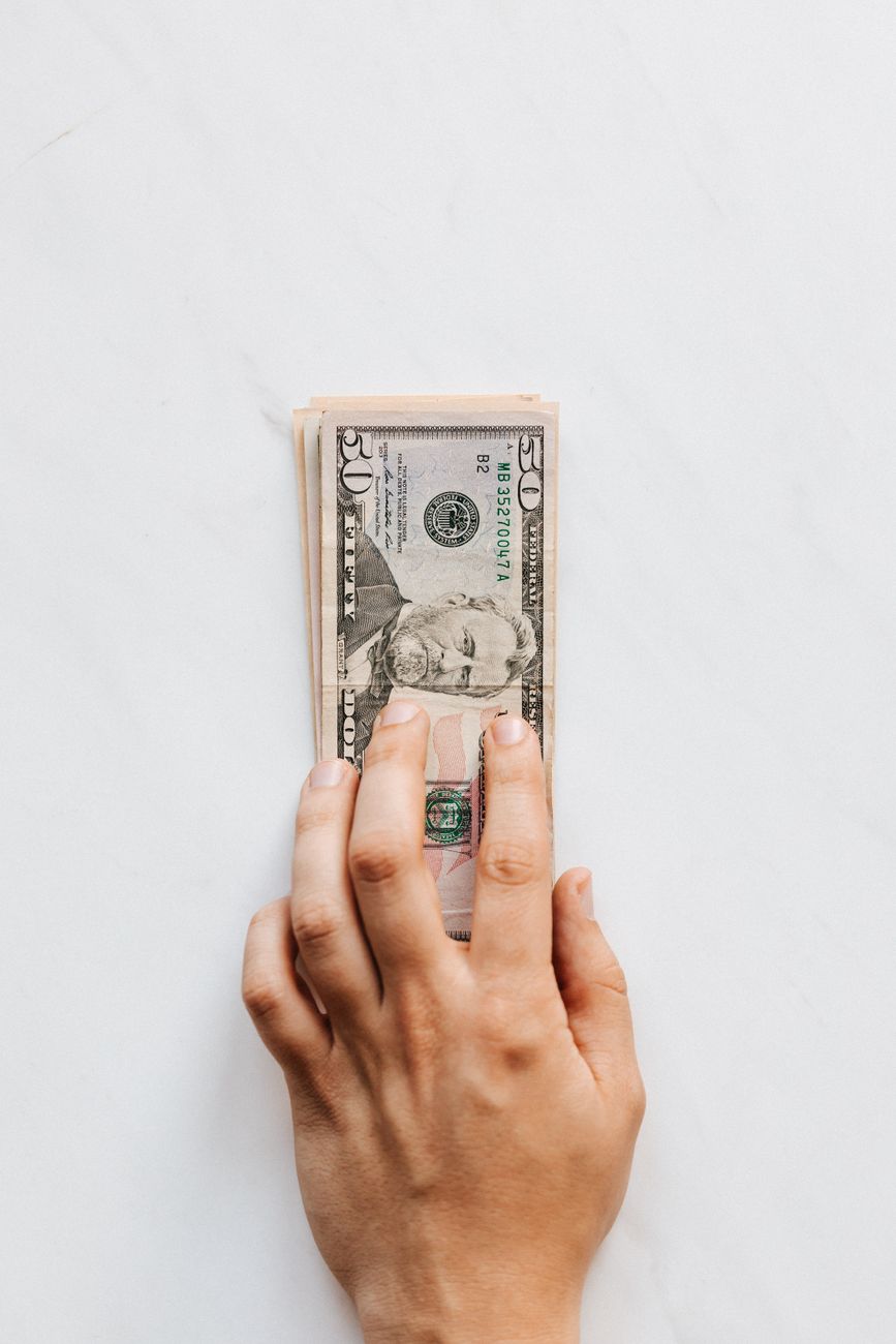 crop unrecognizable person giving heap of greenbacks on marble table