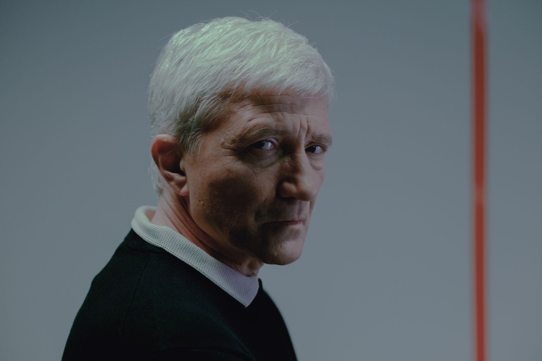 an elderly man in black shirt looking