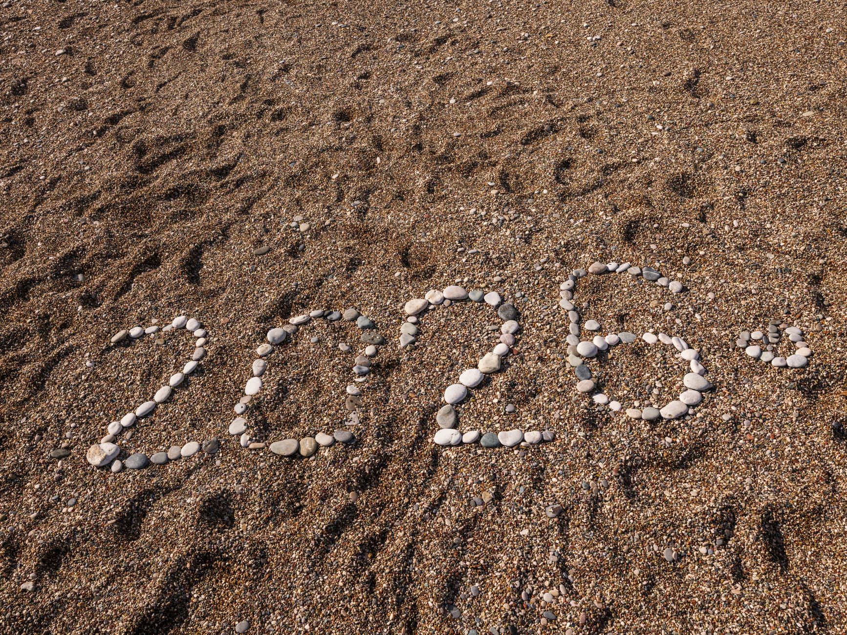Stones arranged to form the number 2026 on a sandy coastline, creating a natural and creative scene.
