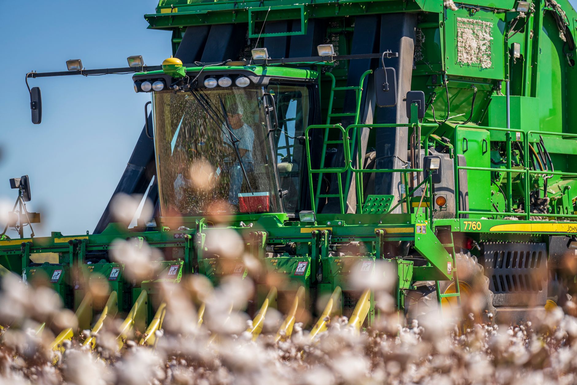 Close-up of a green cotton harvester operating in a field, capturing the machinery in detail.