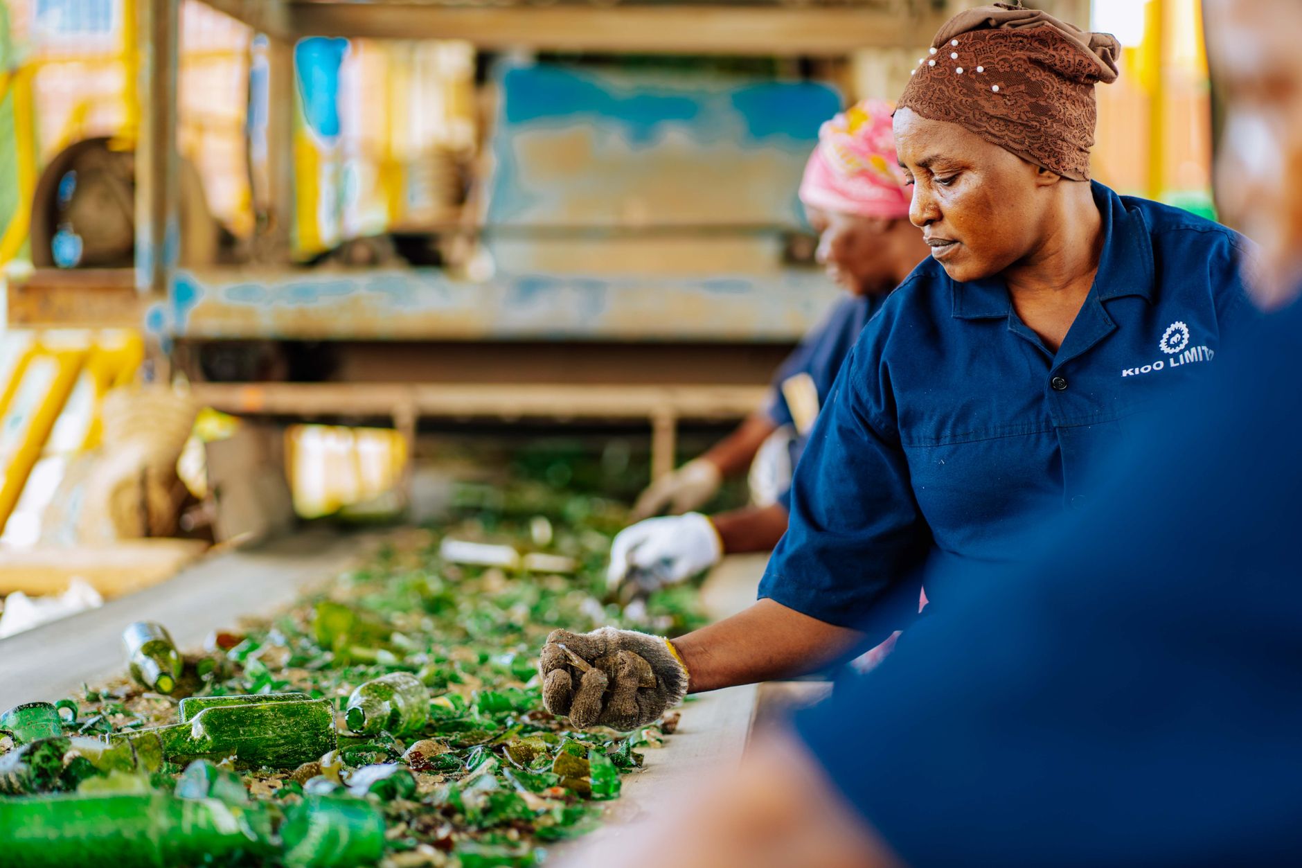 Women sorting broken glass at a recycling facility in Tanzania.