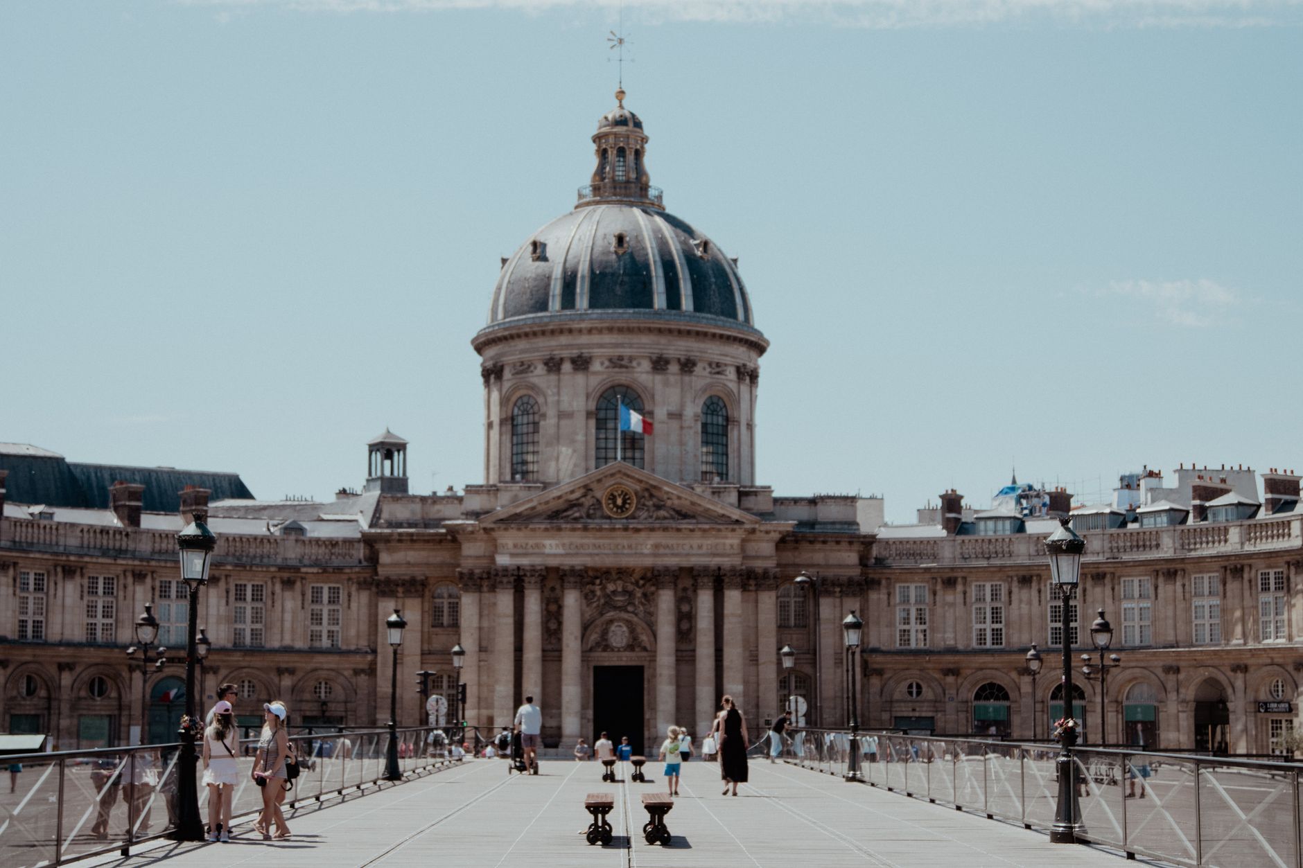 Scene of people crossing Pont des Arts with the iconic Institut de France in Paris, France.