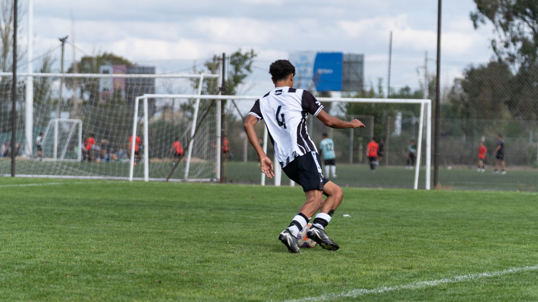 Youth soccer player wearing number 6 in striped jersey, playing outdoors.