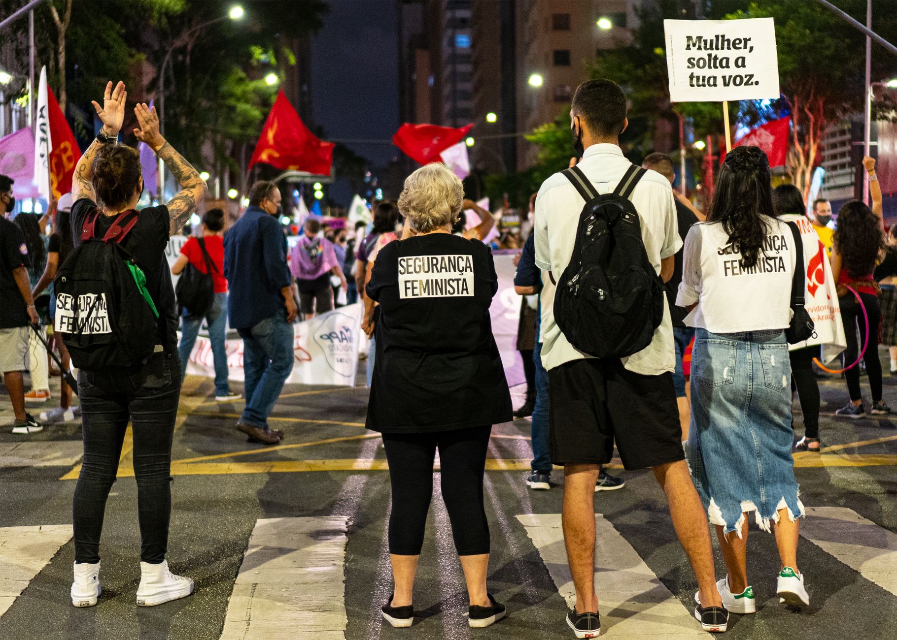 Protesters gather in the city with banners and signs advocating for women's rights and safety.