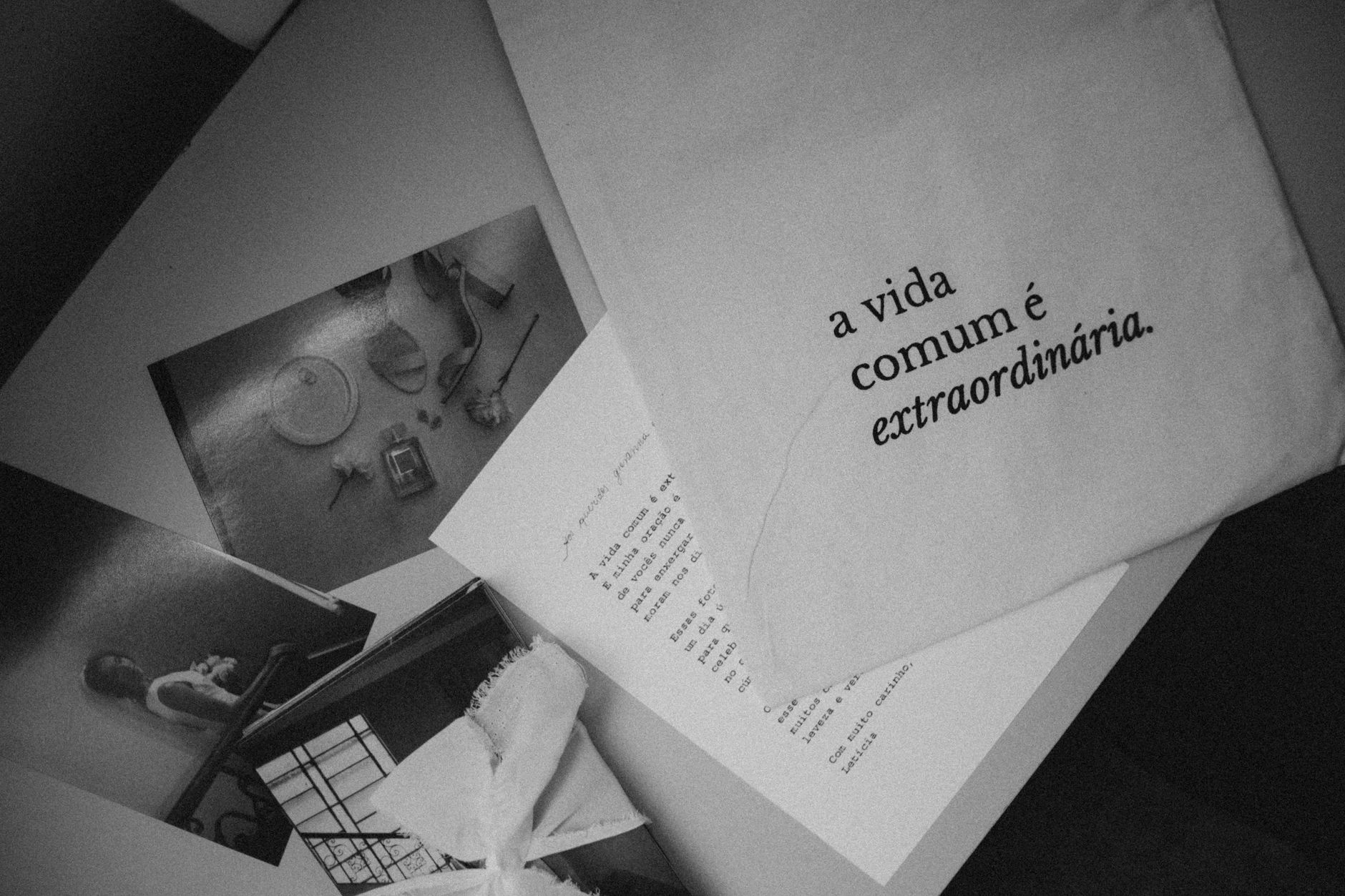 Monochrome still life featuring Portuguese text 'a vida comum é extraordinária' on paper.