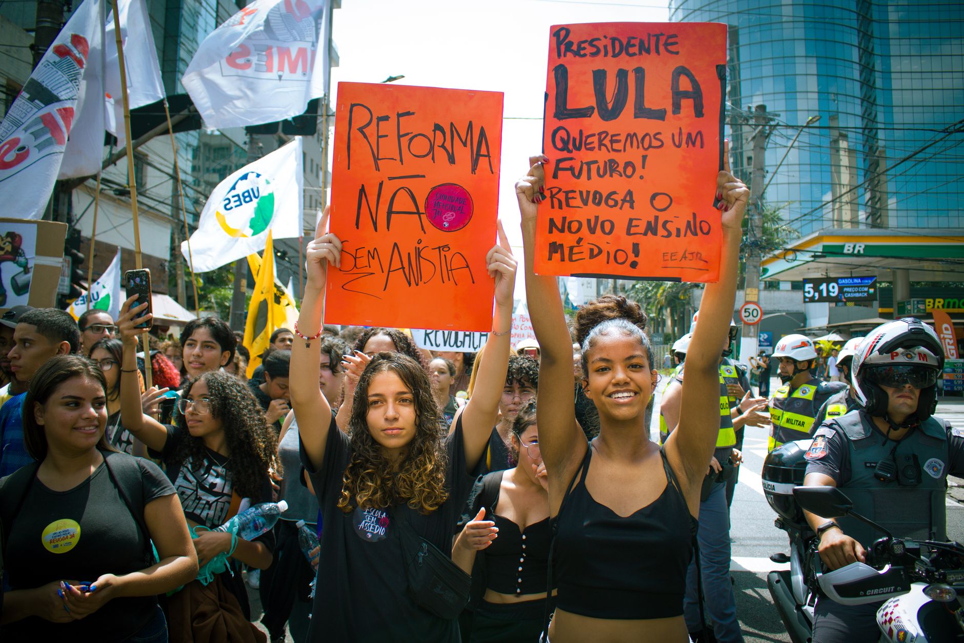 Youth-led street protest with signs advocating educational reform and political change.