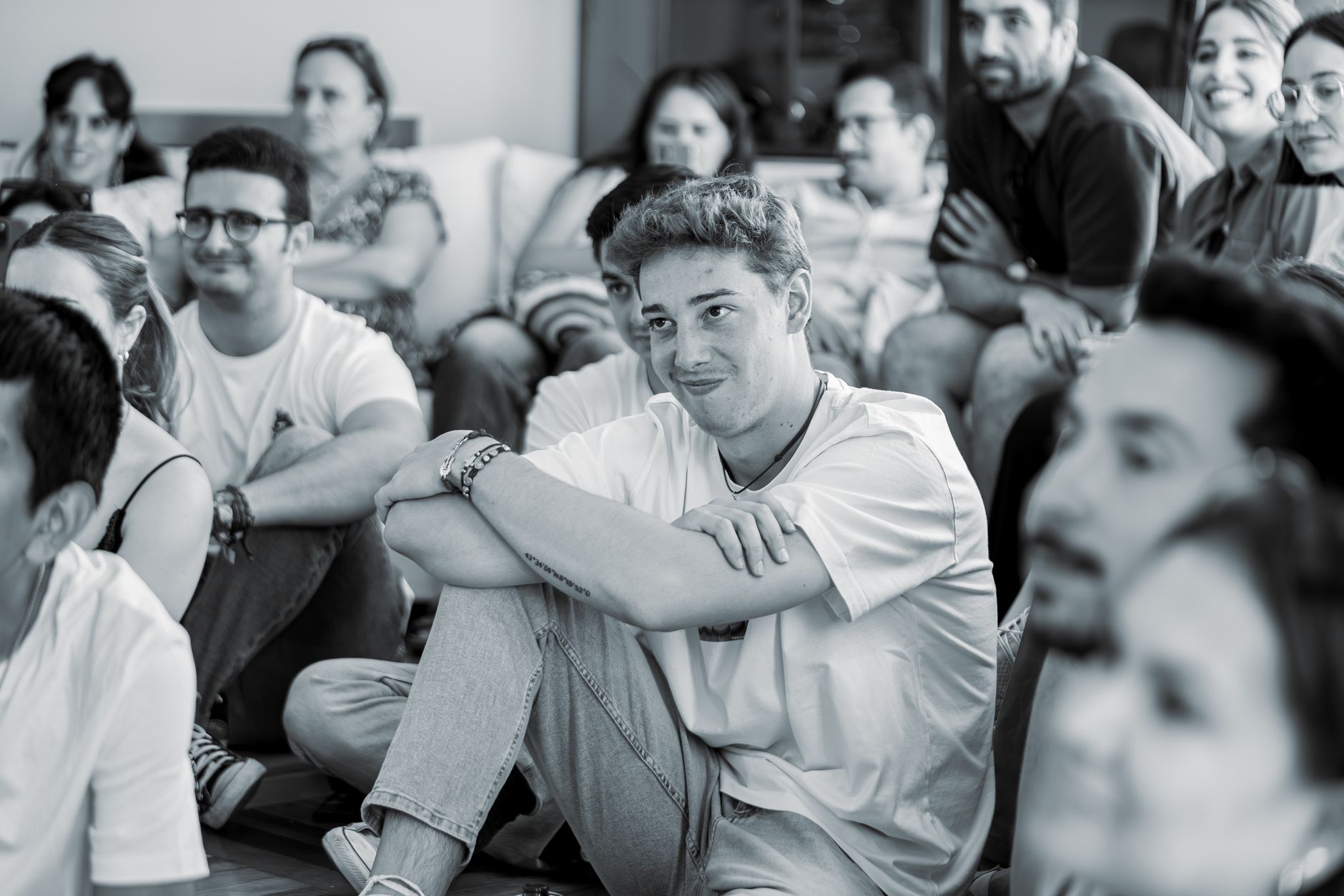 A group of young adults attentively participates in an indoor event, demonstrating active engagement and interest.