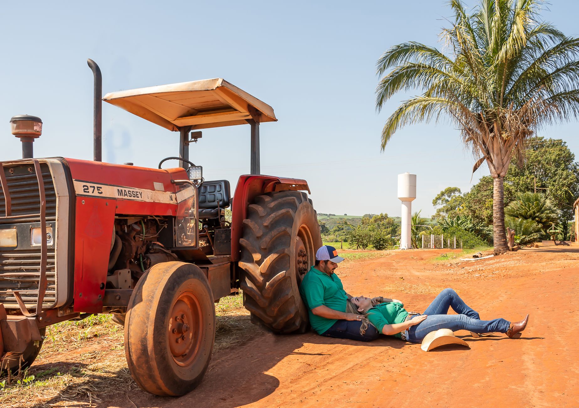 A couple of farmers relaxing near a tractor on a sunny day in the countryside.