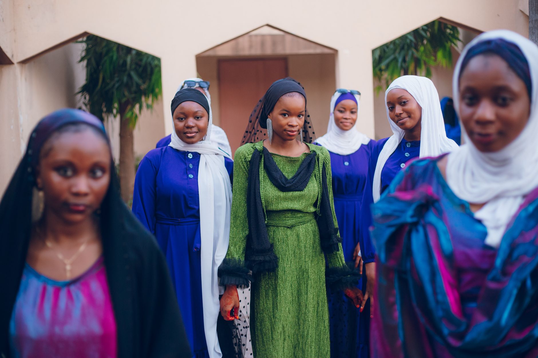 A group of women in colorful traditional attire and veils, posing outside.
