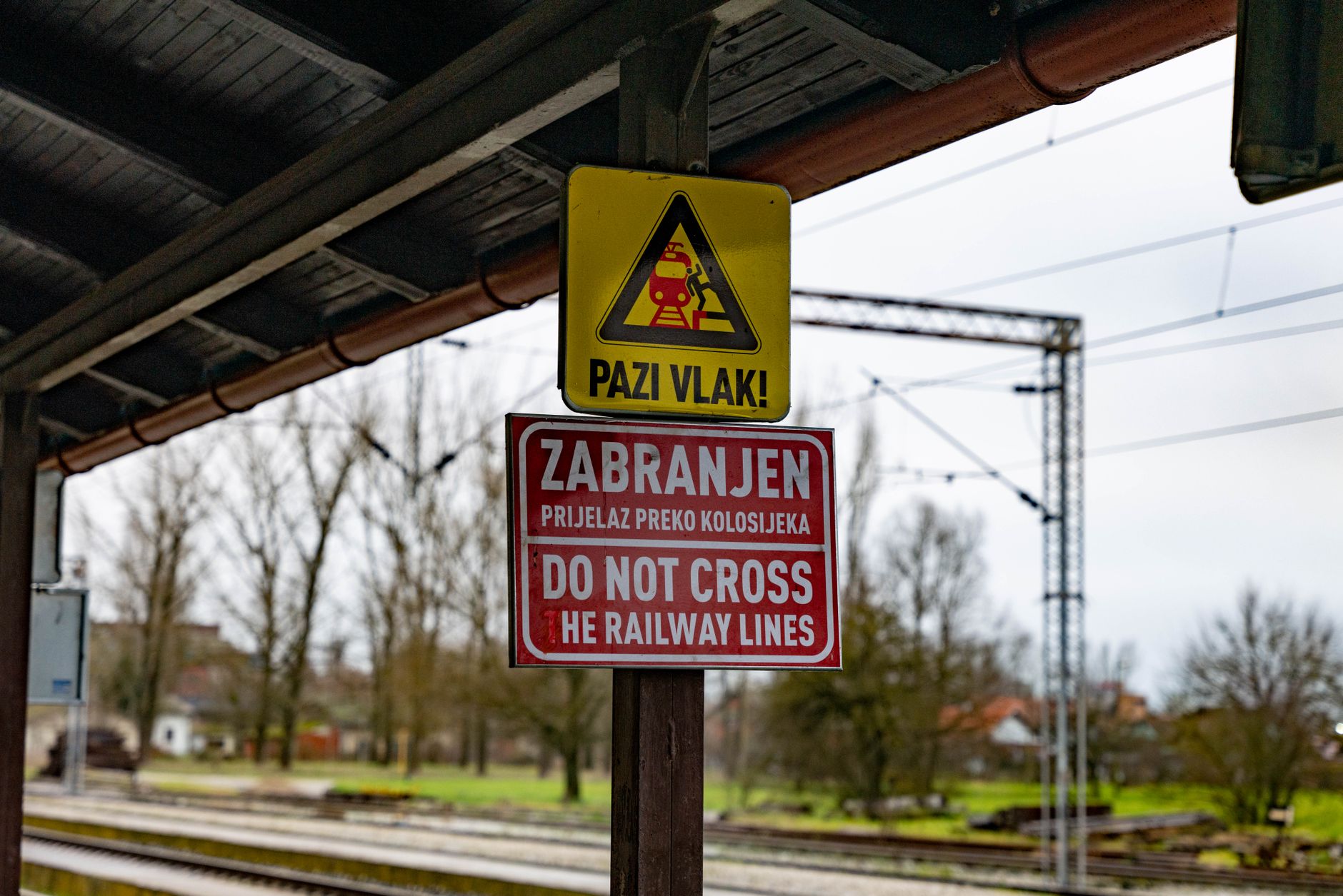 Close-up of warning and 'Do Not Cross' signs at a Croatian railway station.