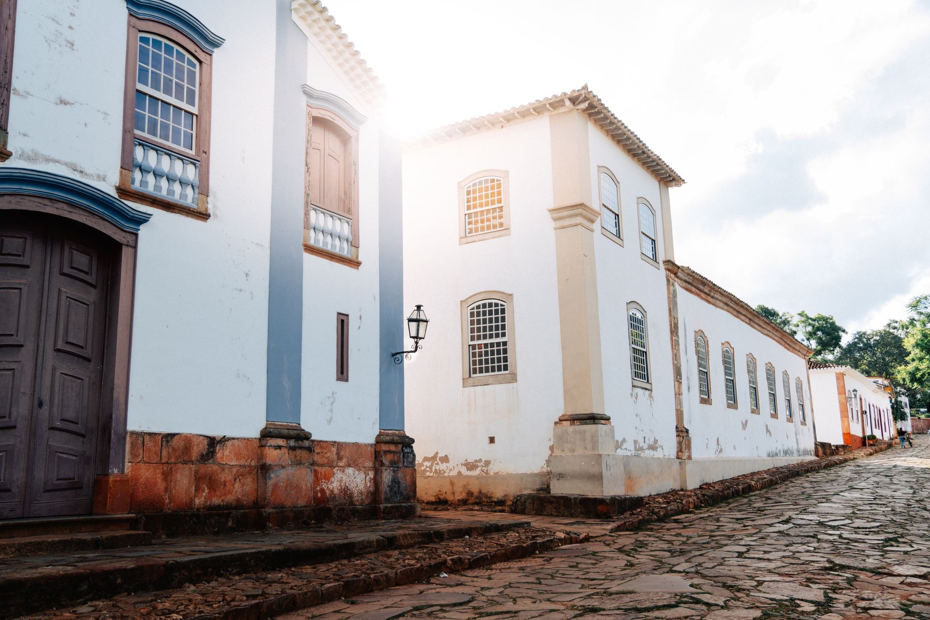 Cobbled street in Tiradentes, Brazil, showcasing colonial architecture bathed in sunlight.