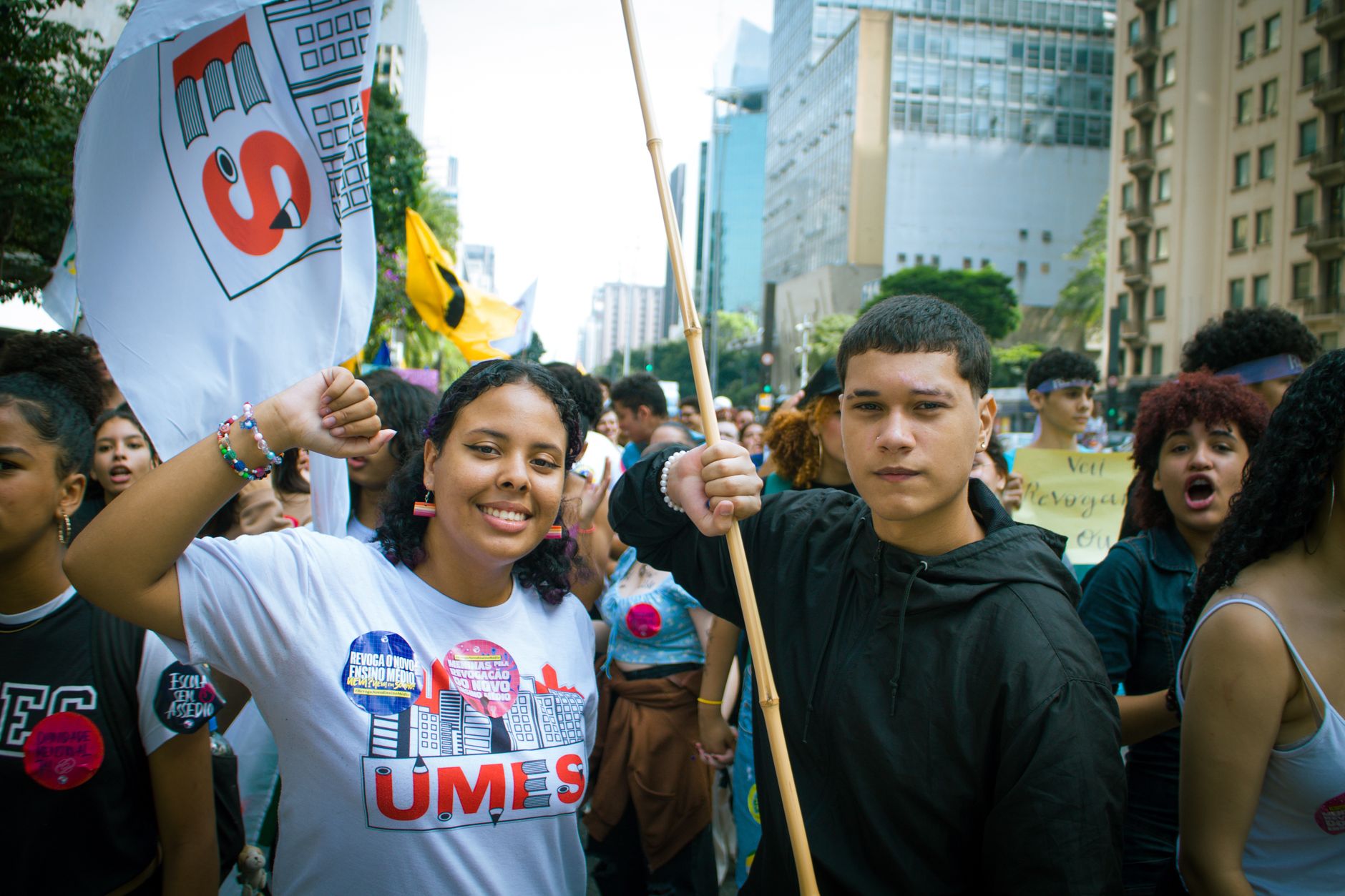 Energetic youth protestors holding flags and signs during a daytime urban demonstration.