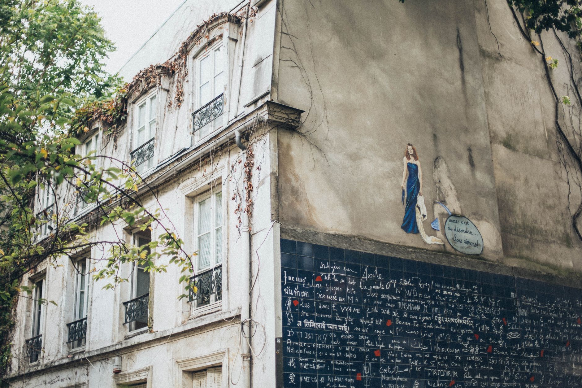 Captivating graffiti mural on an ivy-covered urban building, blending nature and art.