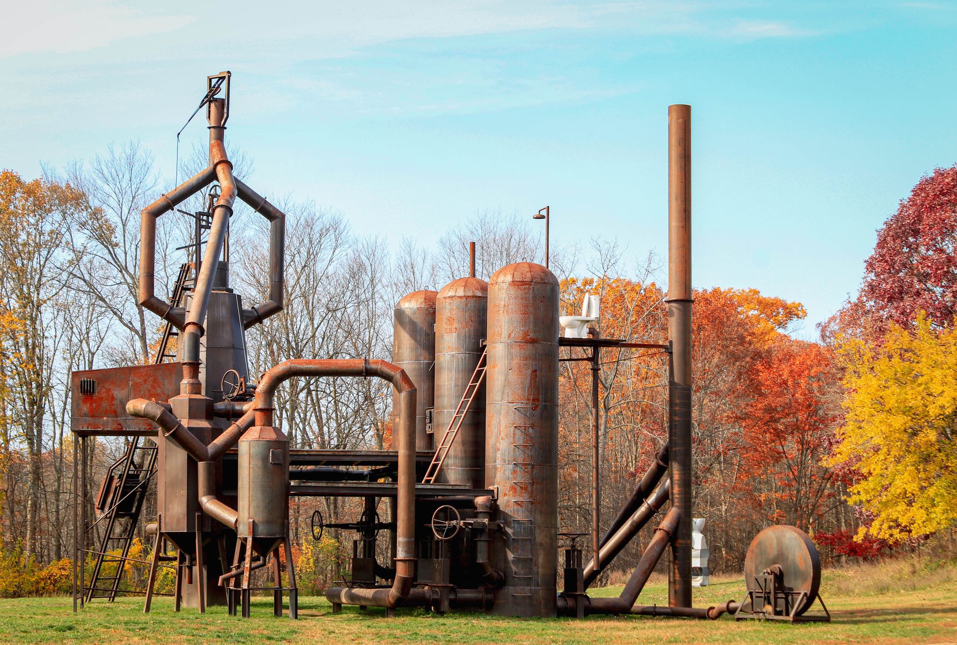 Rust-covered industrial sculpture in an autumn field under a blue sky in Ghent, NY.