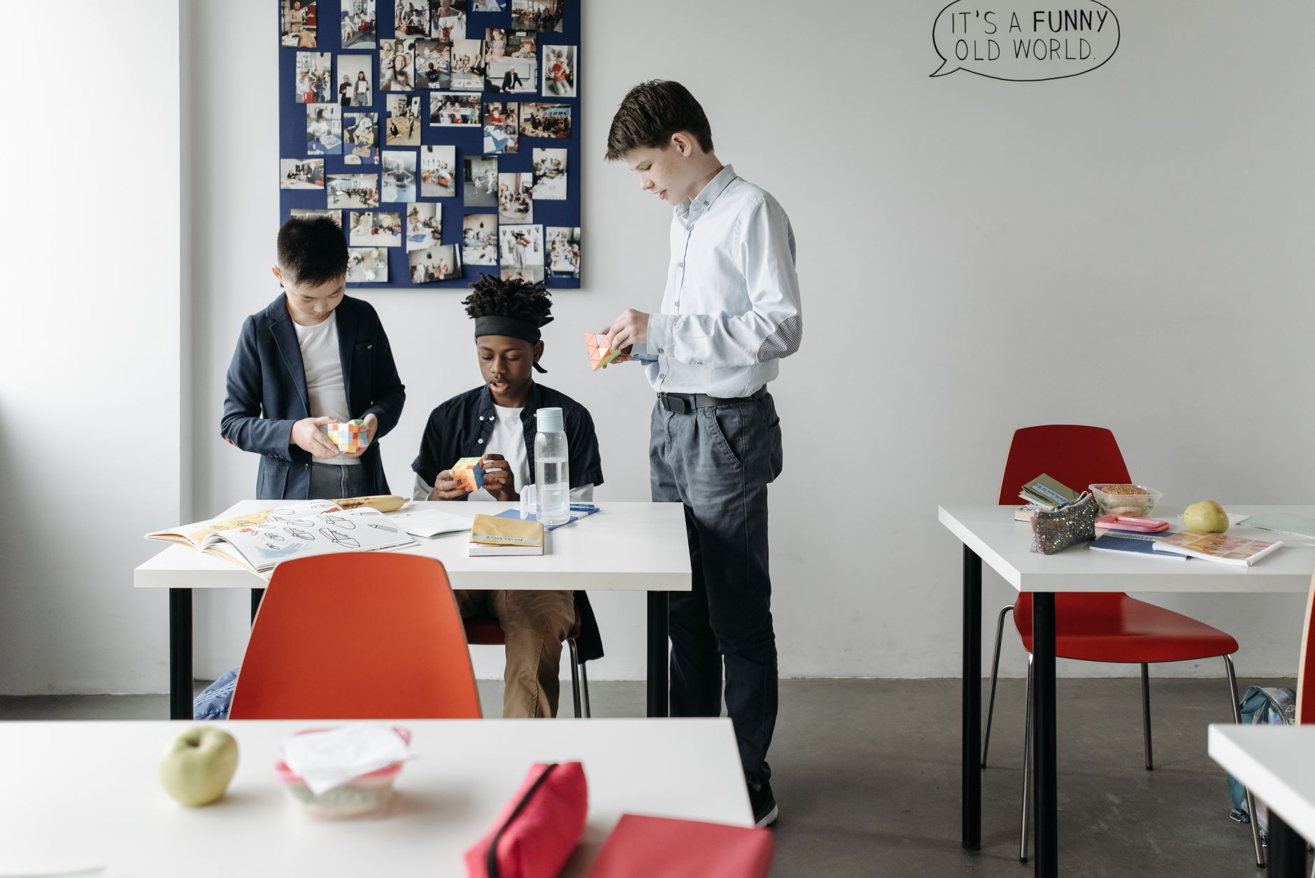 Three diverse students solving Rubik's Cubes in a classroom, fostering teamwork and learning.
