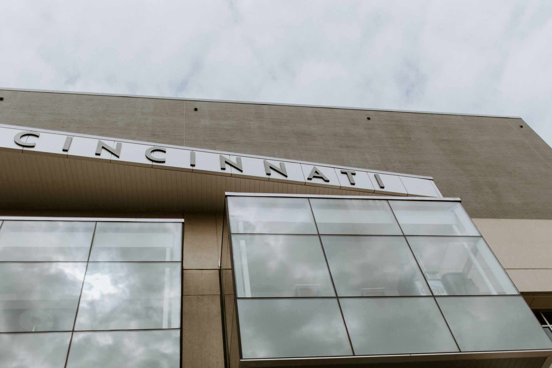 Low-angle view of a modern building with Cincinnati signage and reflective windows.