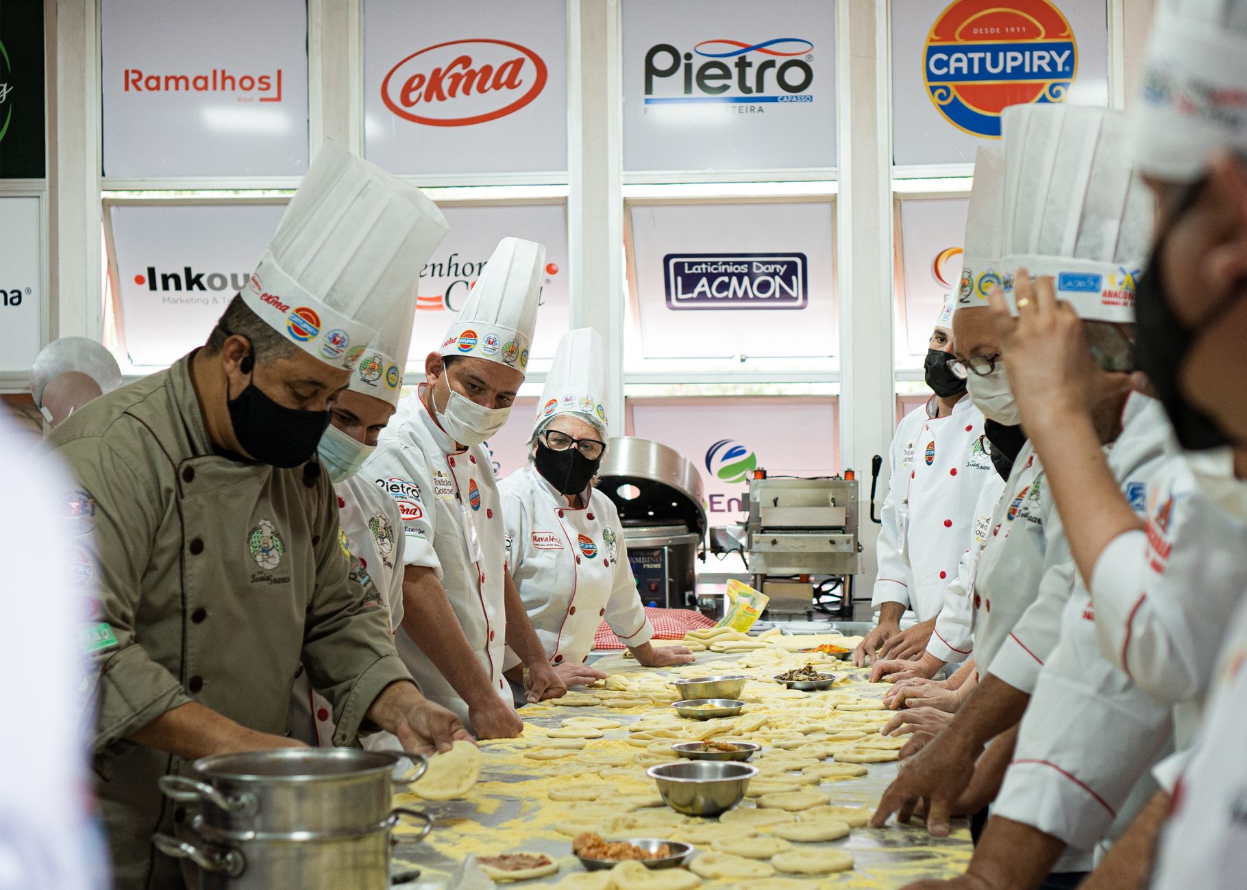 Team of chefs preparing dough for a culinary event in a commercial kitchen setting.