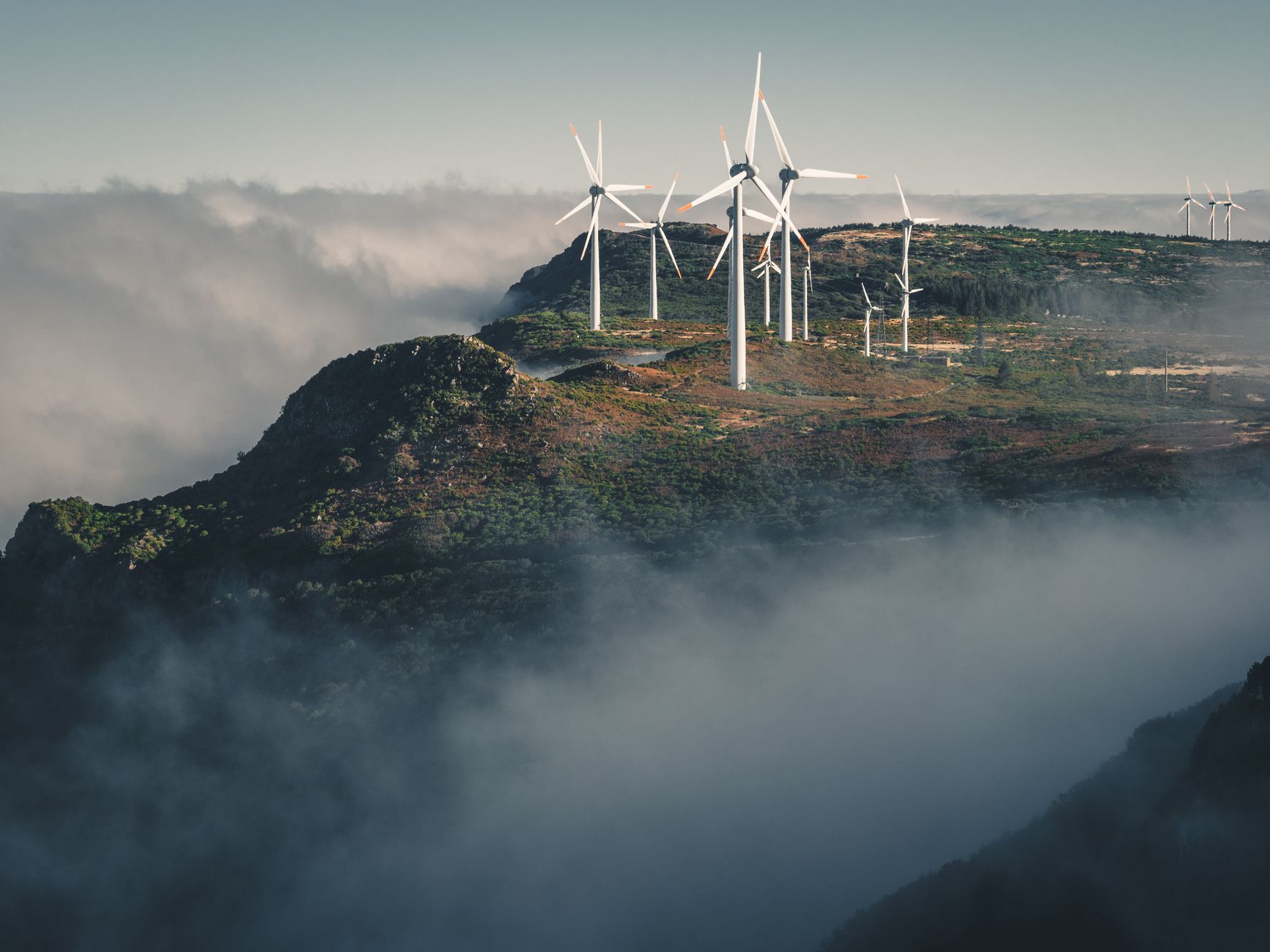 Wind turbines amidst fog and clouds in Madeira, Portugal create a captivating natural scene.