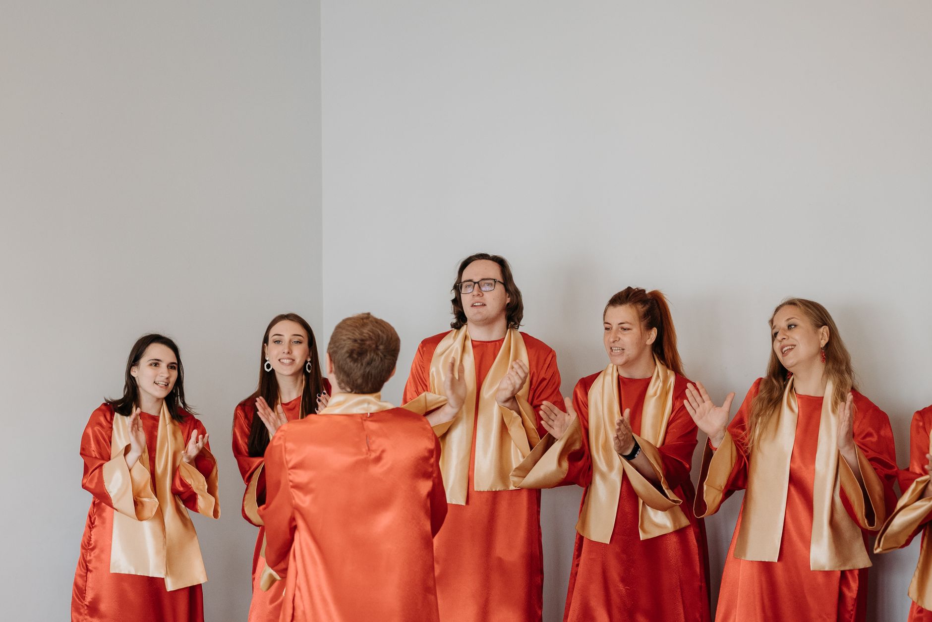 A diverse group of young choir members singing together indoors.