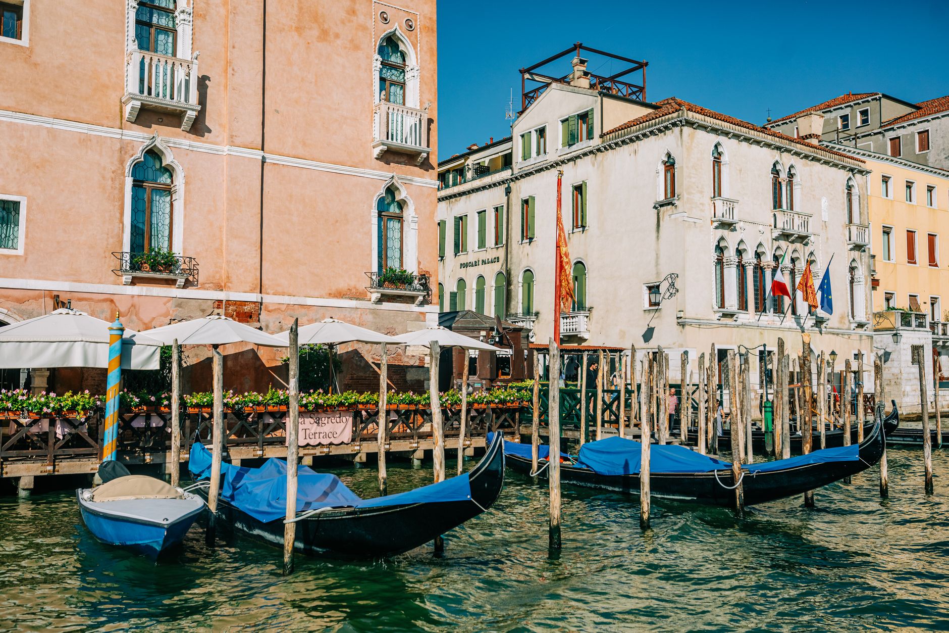 Picturesque scene of gondolas along a Venetian canal. Summer day with colorful buildings and water reflections.