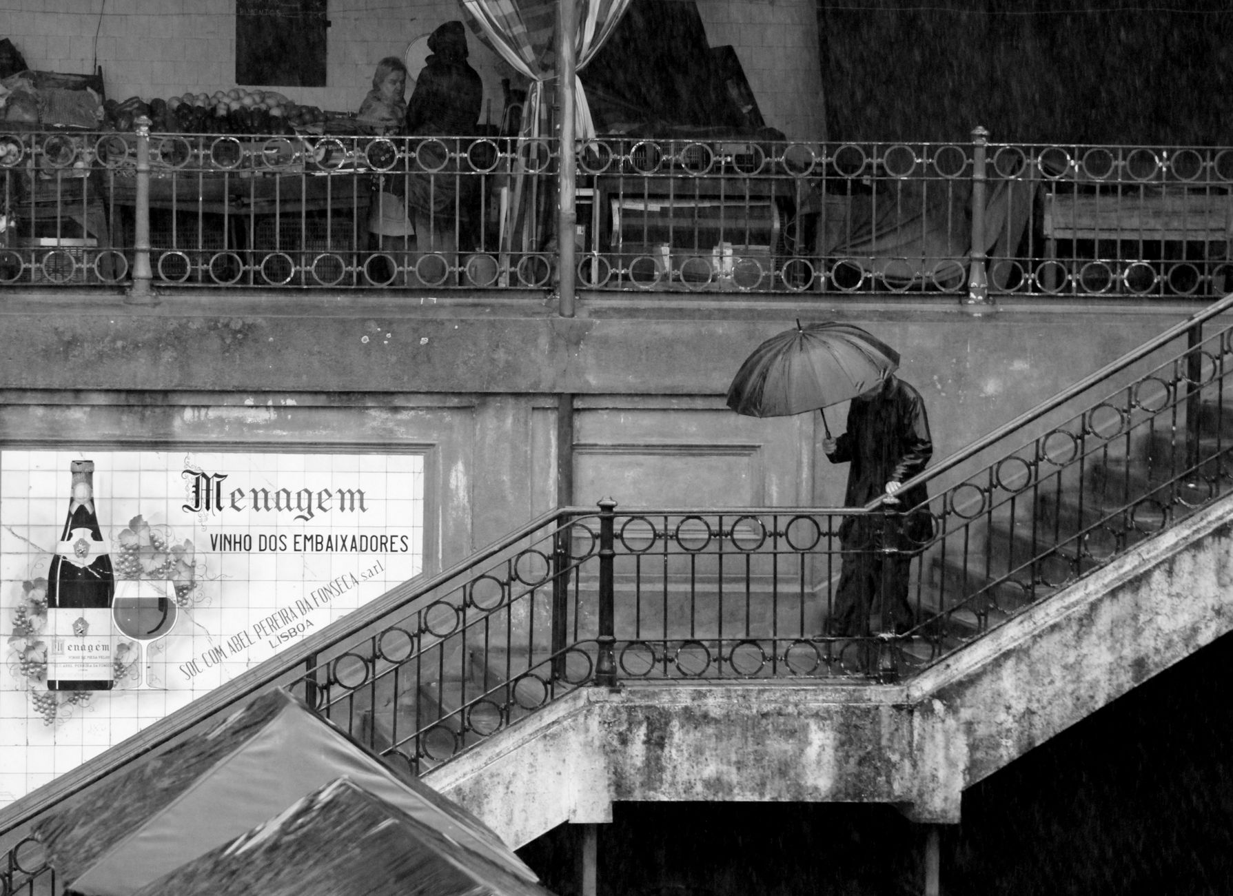 Atmospheric street scene capturing a person with an umbrella on a rainy day in Lisbon.