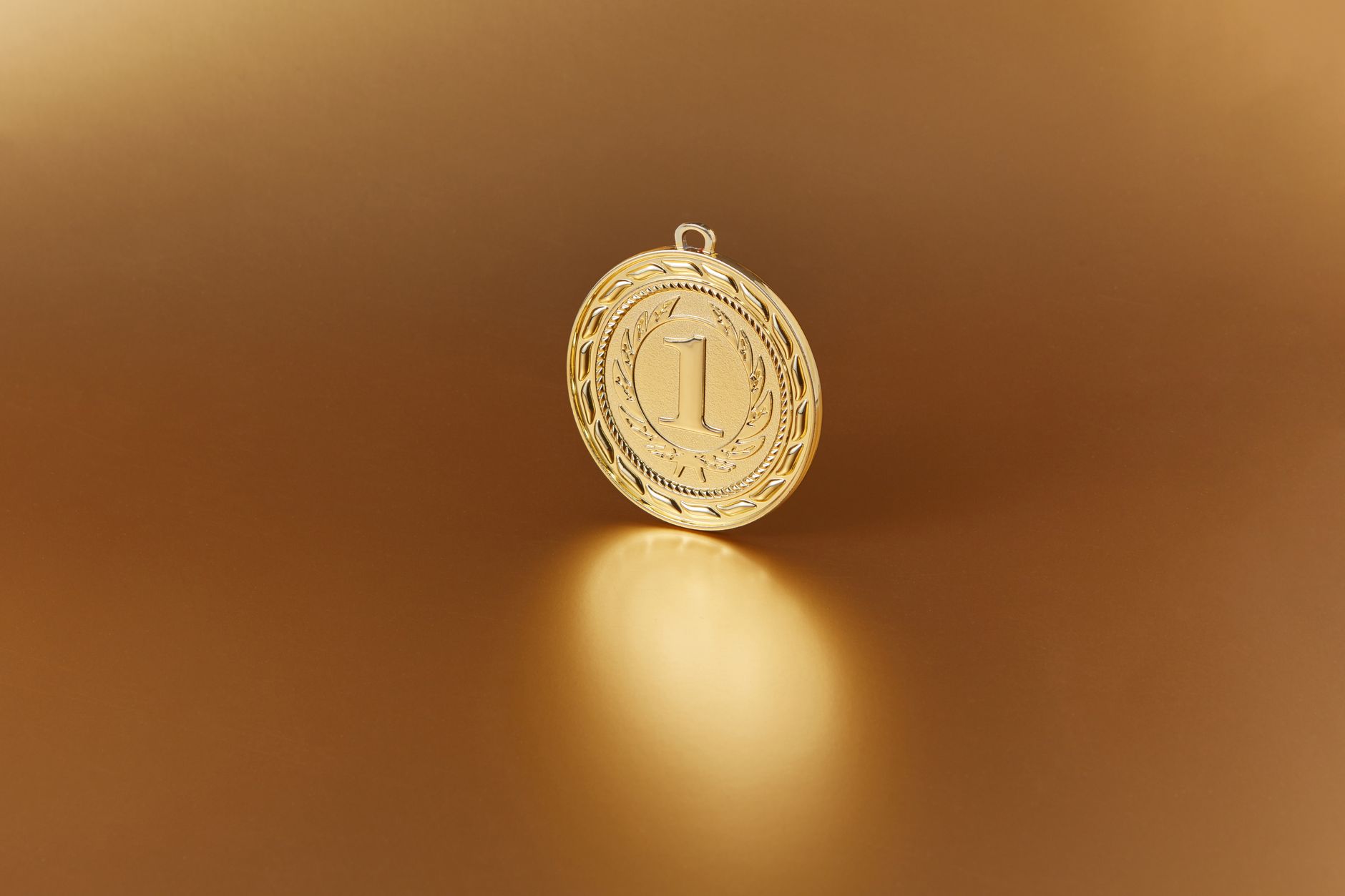 Close-up image of a golden number one medal on a soft golden background.