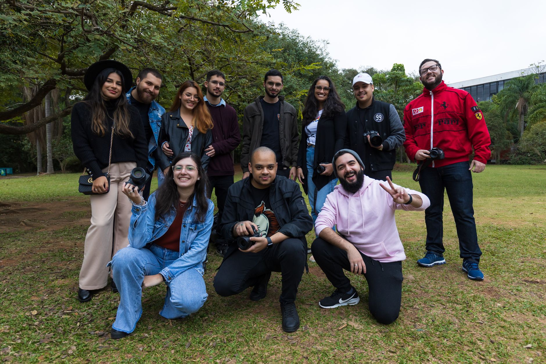 Diverse group of friends with cameras enjoying a photography meetup in a lush park setting.