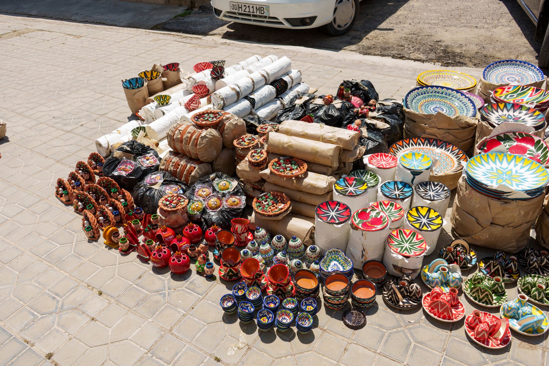 Vibrant handmade ceramics displayed outdoors in Samarkand's bustling market.